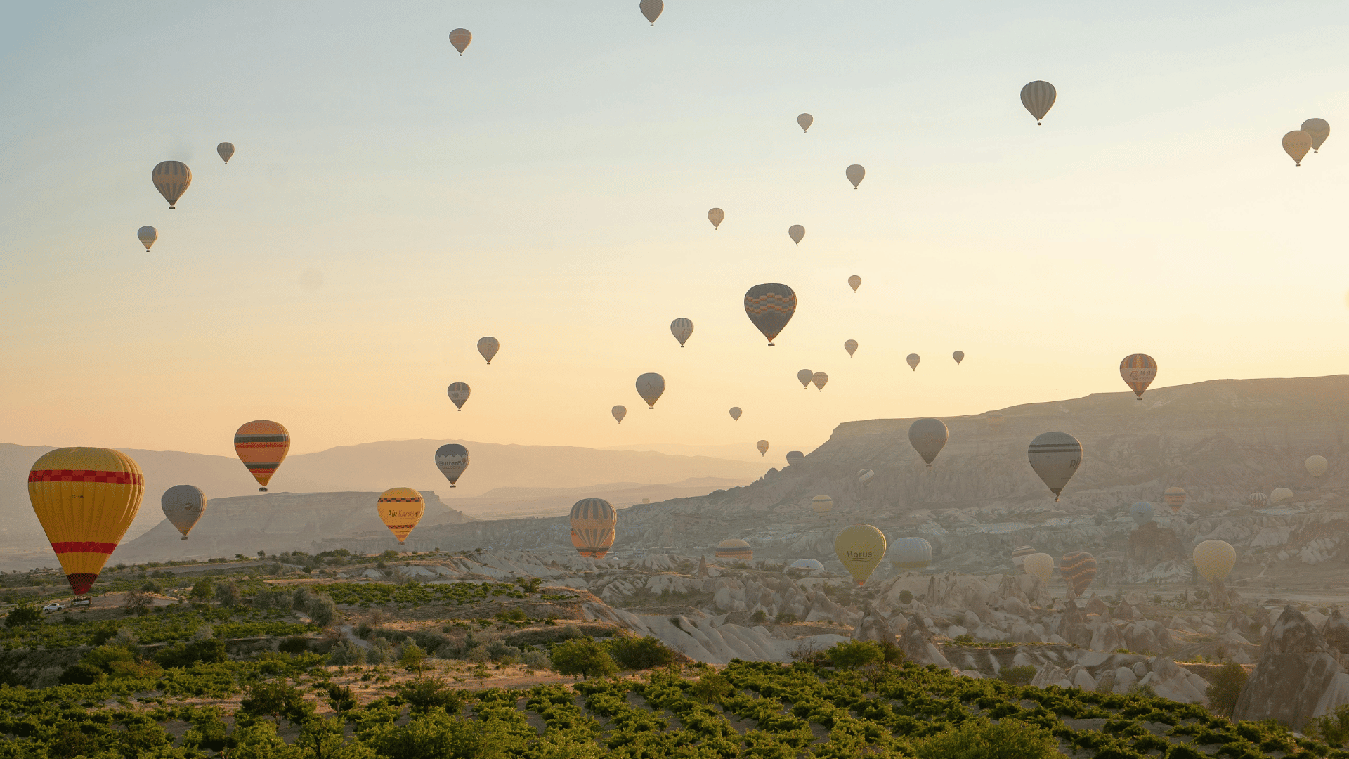 Atemberaubende Küstenlandschaft mit Heißluftballons bei Sonnenuntergang